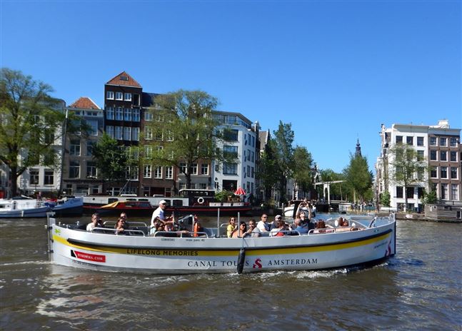 Vista lateral de un recorrido en barco abierto en verano de Canal Tours Amsterdam