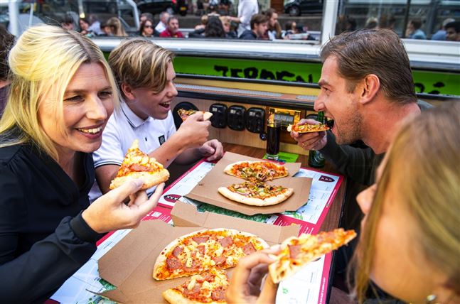 Una familia disfruta de una pizza durante un crucero por los canales de Ámsterdam