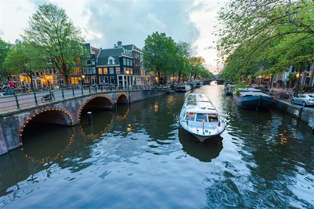 Toma nocturna de Canal Tours cerca de los puentes de Ámsterdam