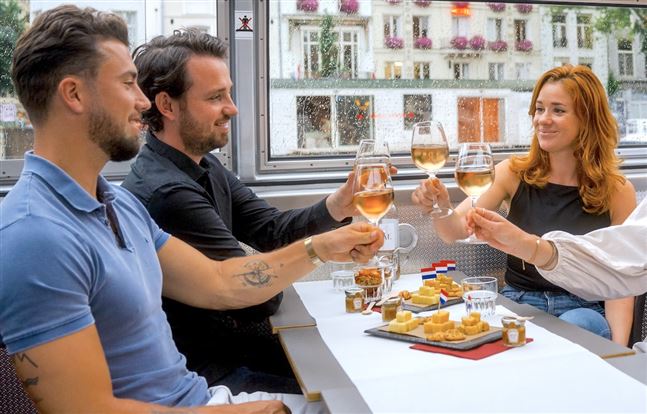 Un grupo de amigos disfruta del queso y el vino durante un recorrido por los canales de Ámsterdam