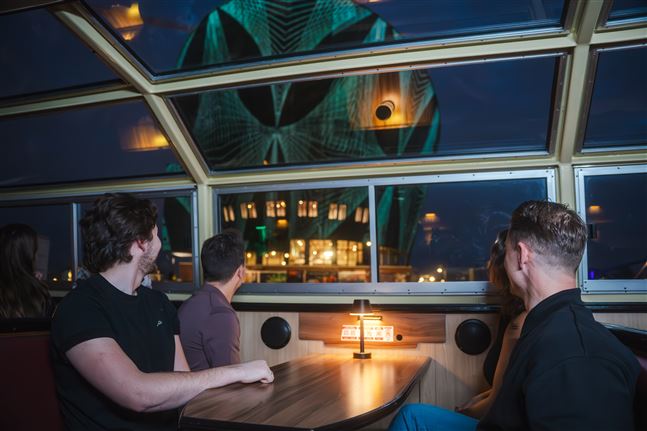 Vier vrienden kijken naar lichtkunst geprojecteerd op het NEMO museum