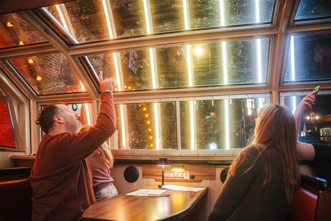 Een vader wijst naar een lichtkunstinstallatie om zijn dochter te laten zien aan boord van een cruise